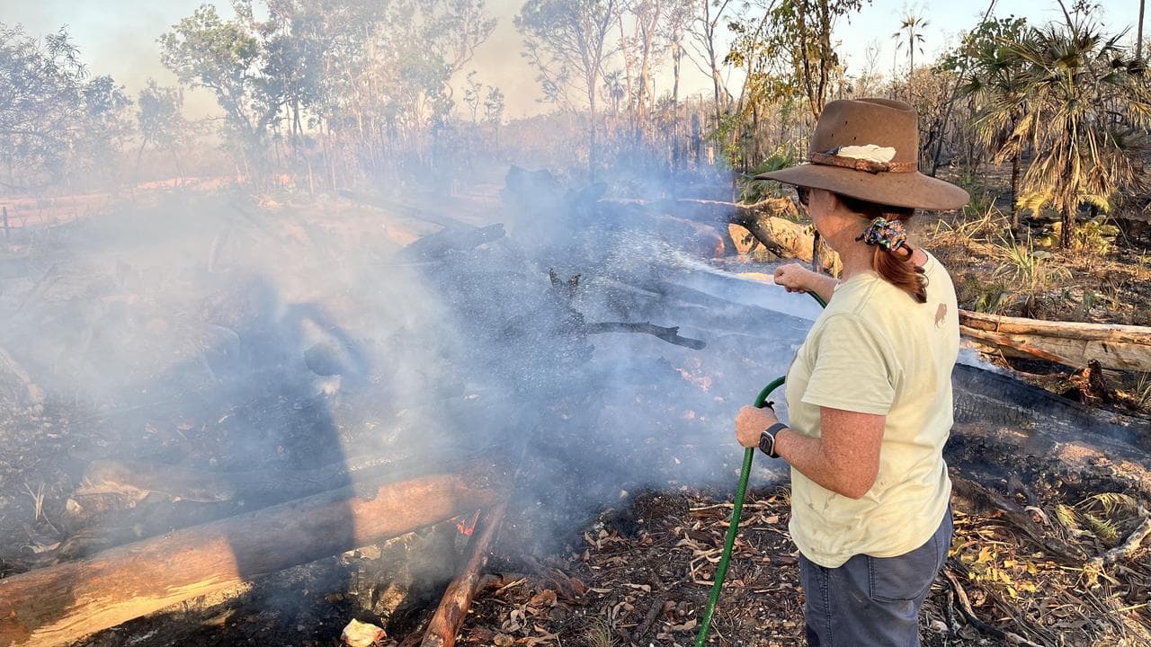 A resident hoses down burnt bushland.