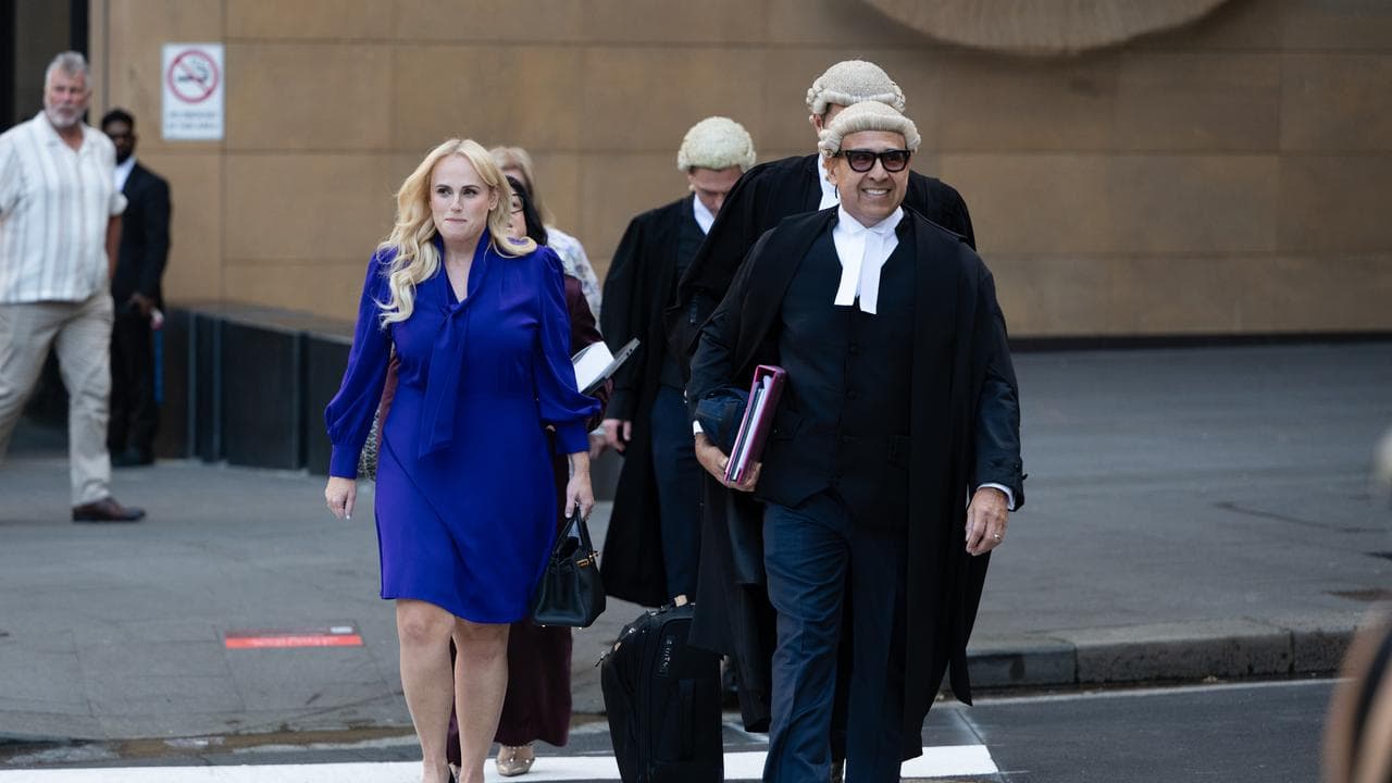 Rebel Wilson and robed lawyers cross street 