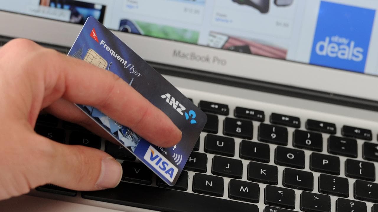A credit card is held in front an online shopping site