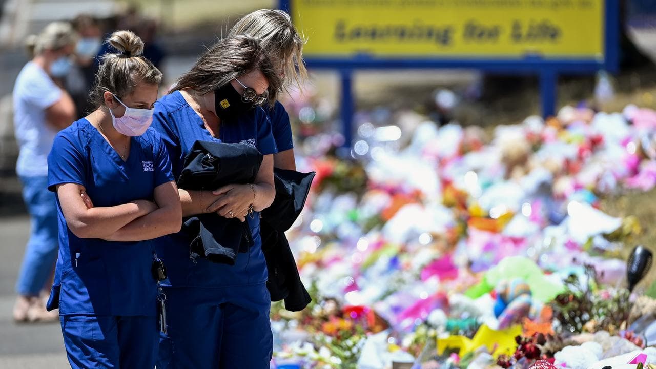 Health care workers look at floral tributes