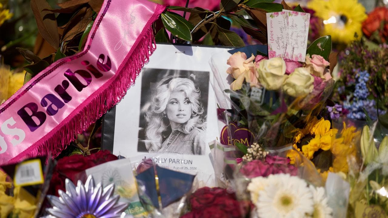 A portrait of Dolly Parton with flowers outside her home in Tennessee