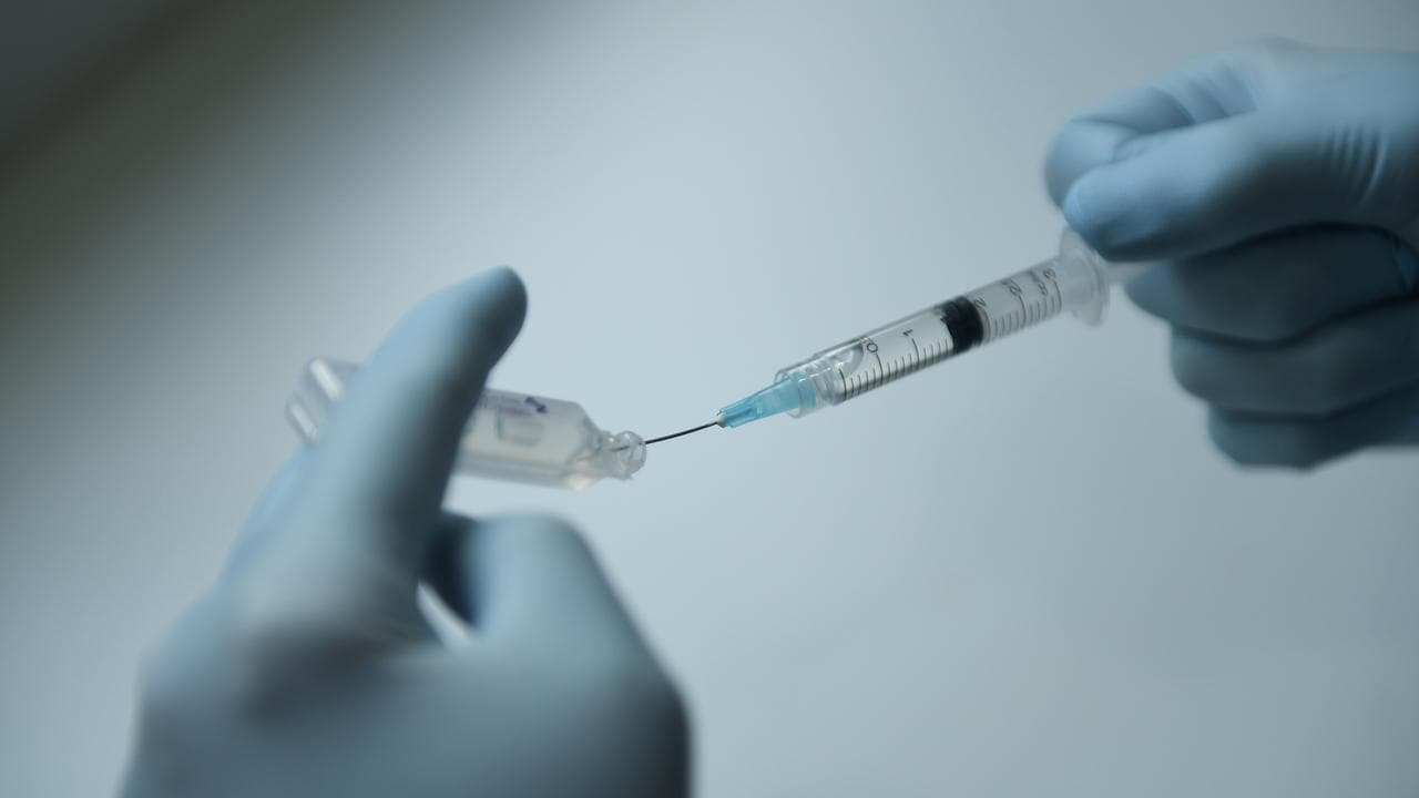 A doctor drawing fluid into a syringe (file)