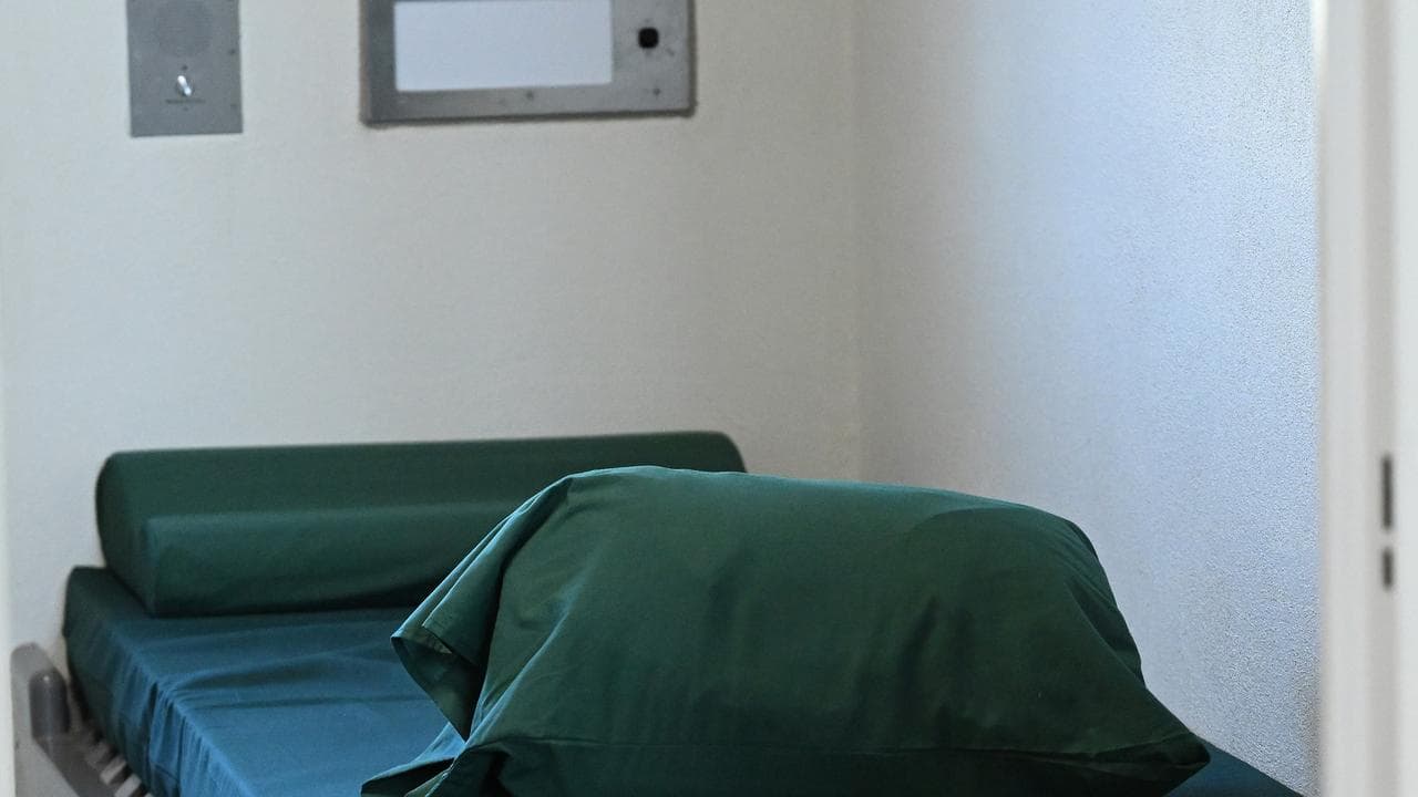 A bed is seen in a prison cell