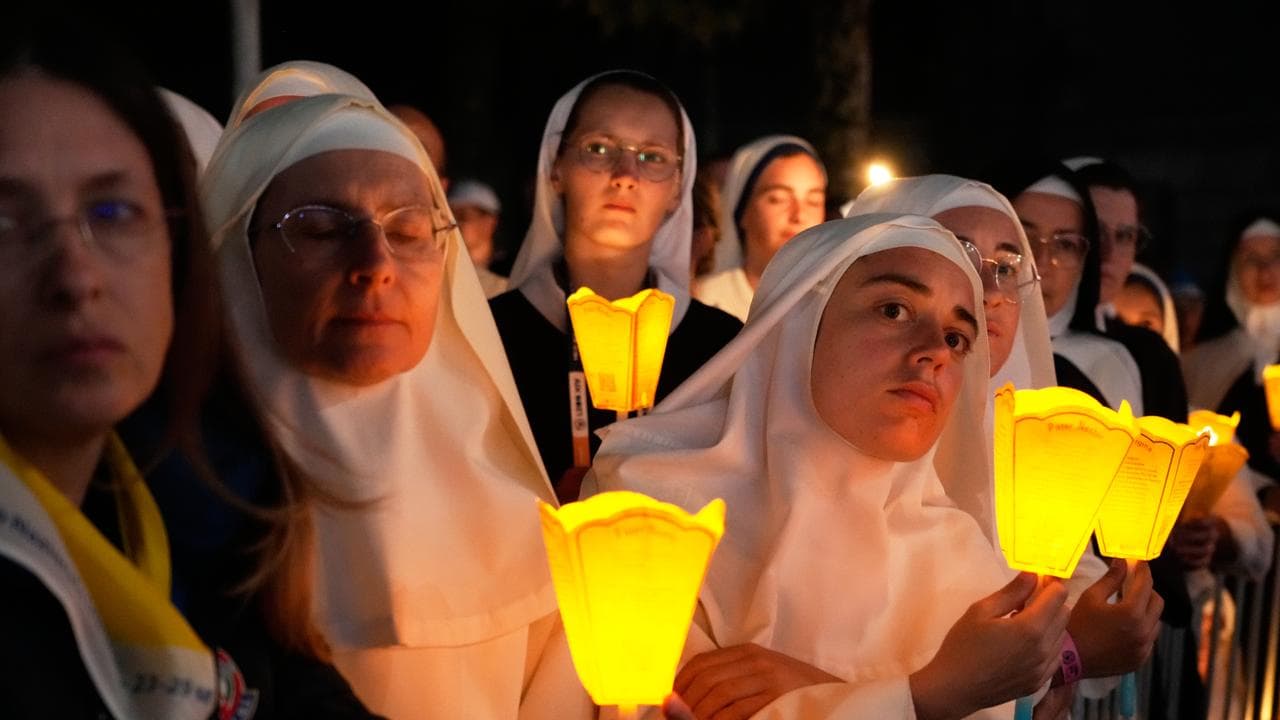 Nuns hold candles as they attend a prayer of the Holy Rosary