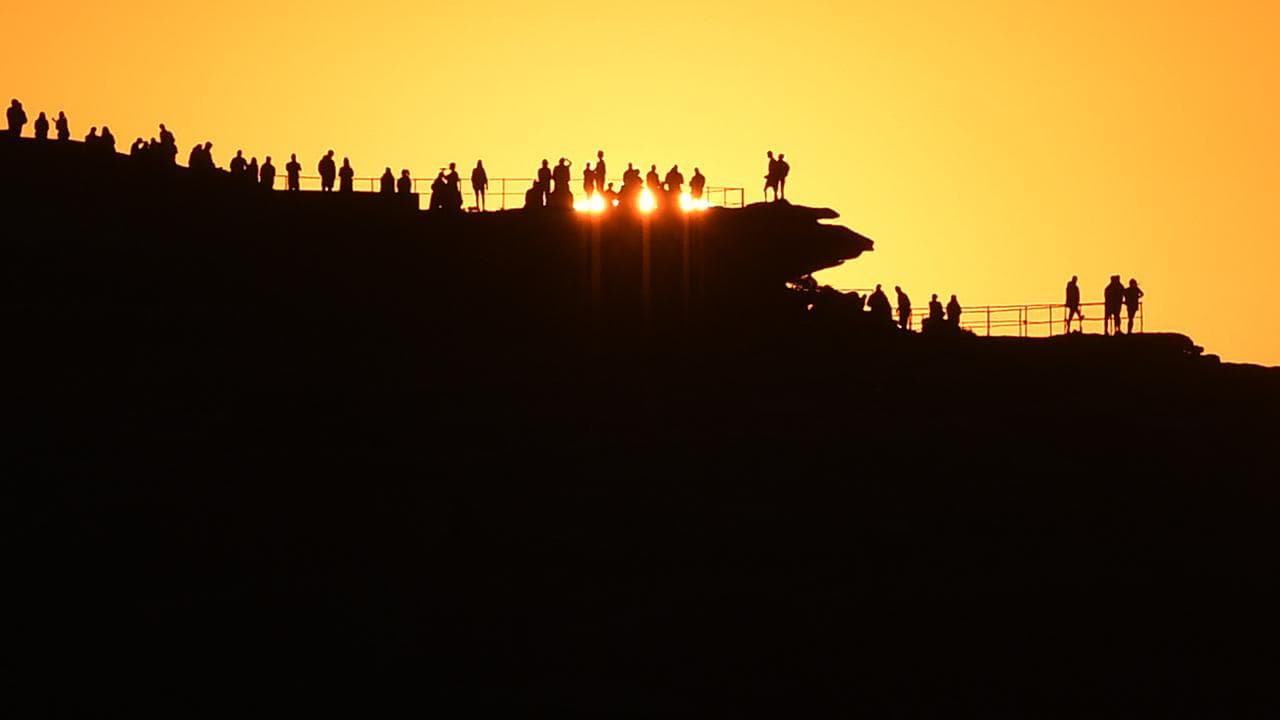 People watch sunrise at Bondi Beach in Sydney, NSW
