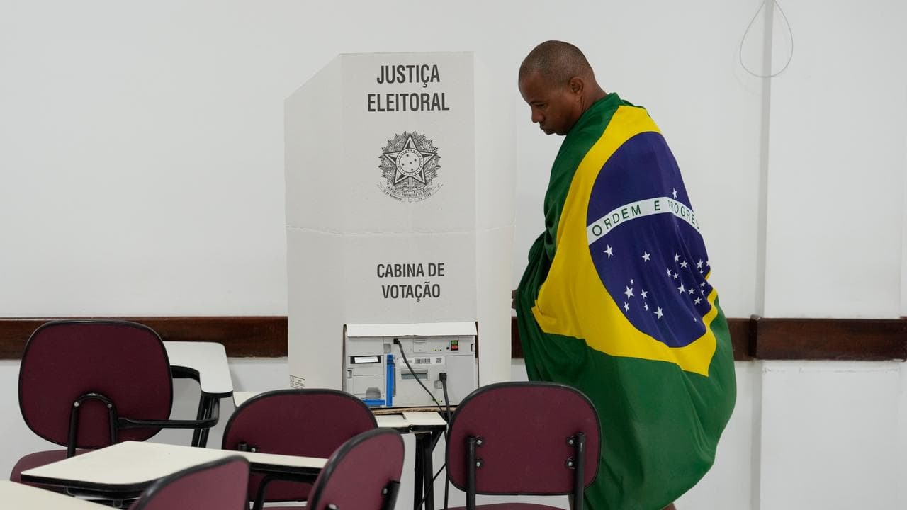 A voter wrapped in a Brazilian flag prepares to cast his ballot