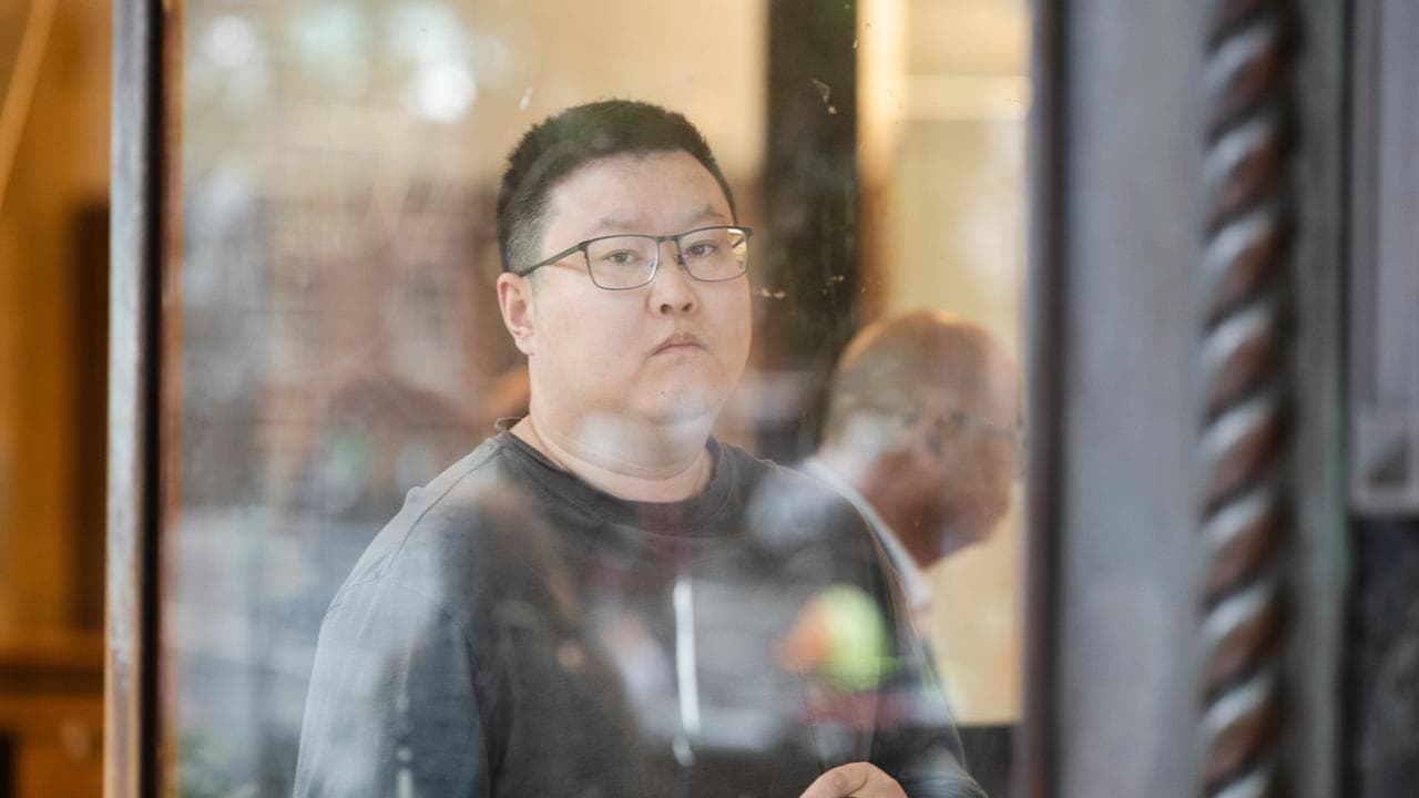 young man holding phone looks at camera
