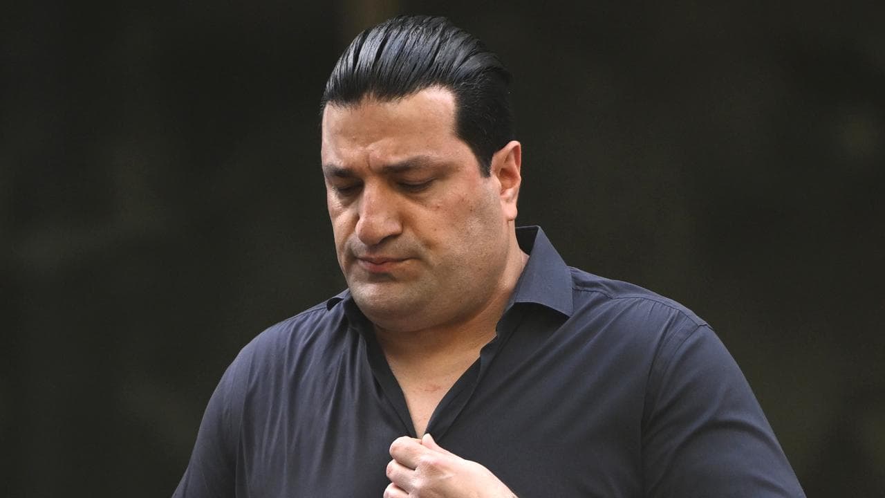 man with slicked back hair holds shirt