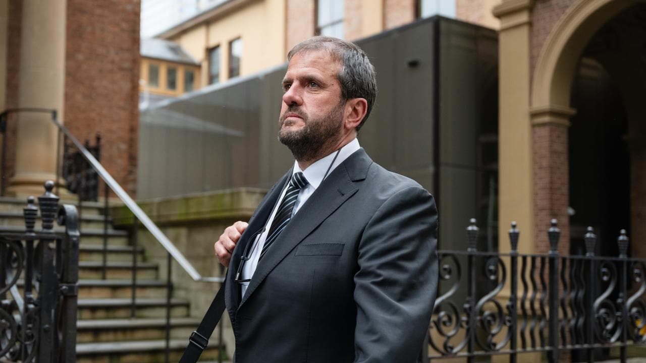 man looks up walking past church