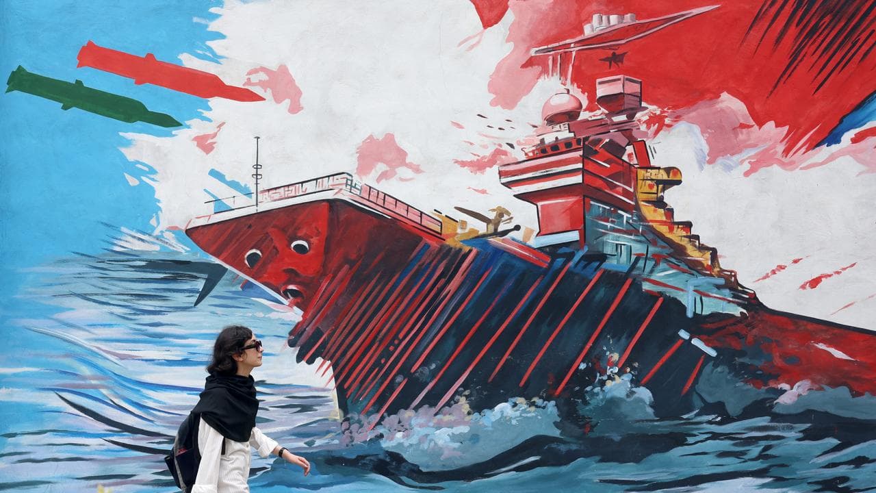 A woman walks next to anti-US graffiti on a street in Tehran