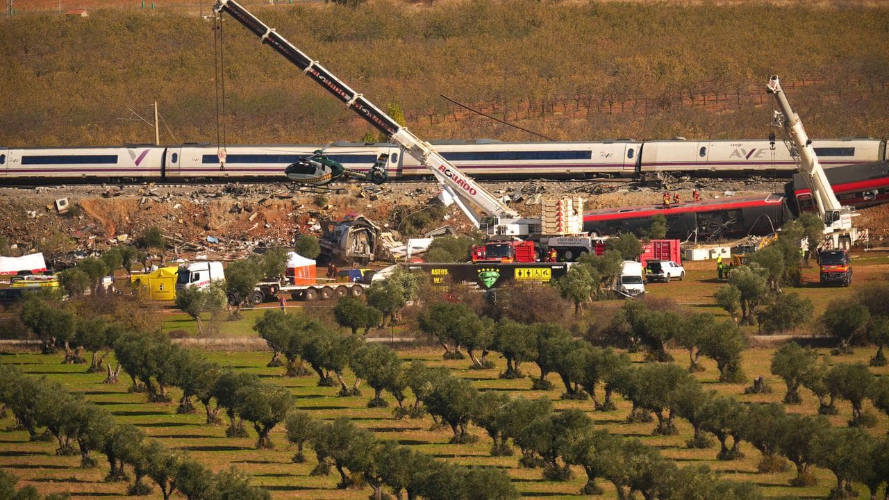 Cranes lift wrecked carriages after a train collision near Urda, Spain