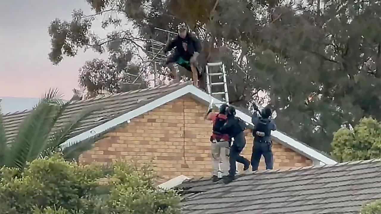 Man charged with murder after rooftop stand-off
