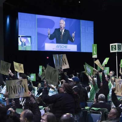 Flying solo, Walz takes election fight to Trump